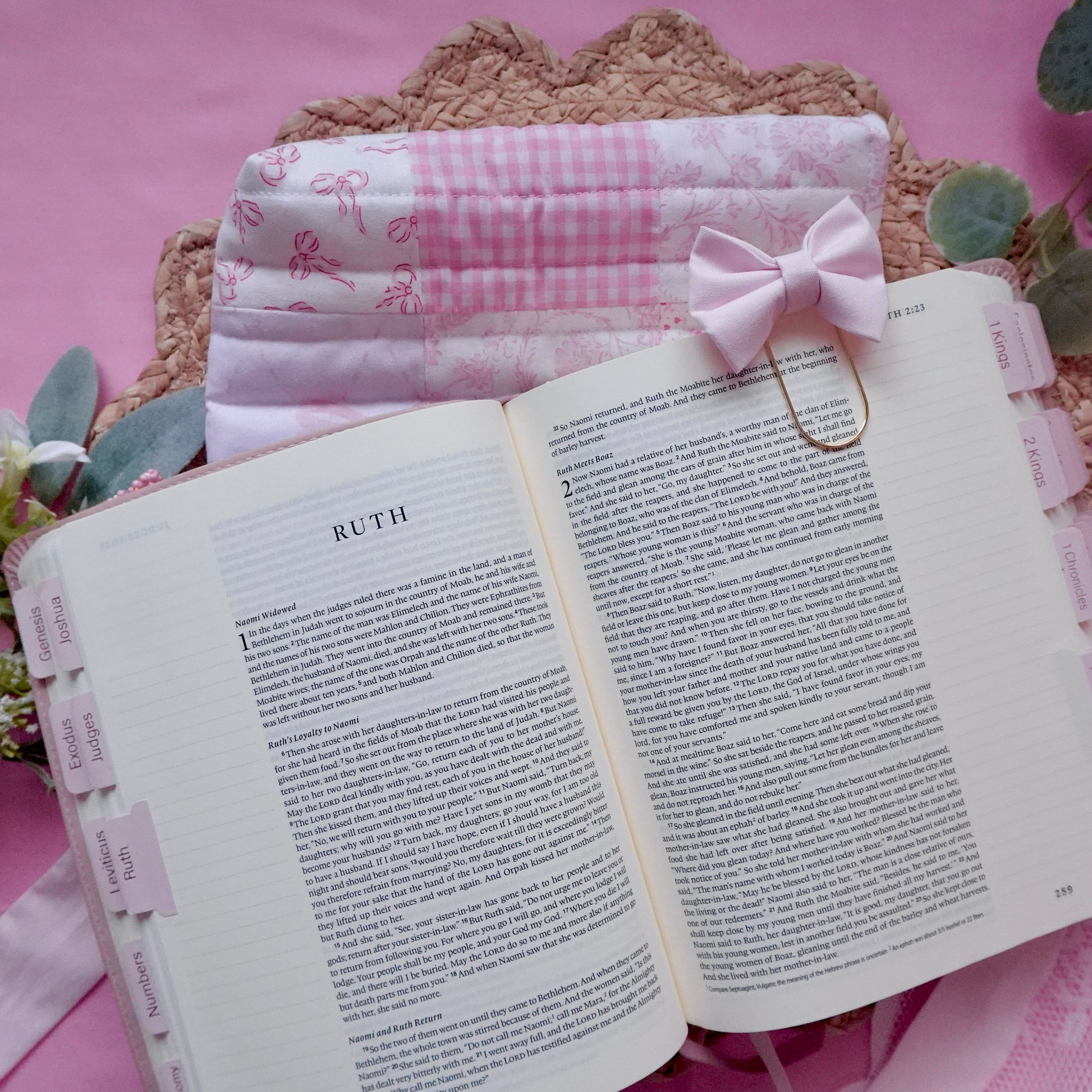 Open book with pink ribbon and decorative elements on a pink background